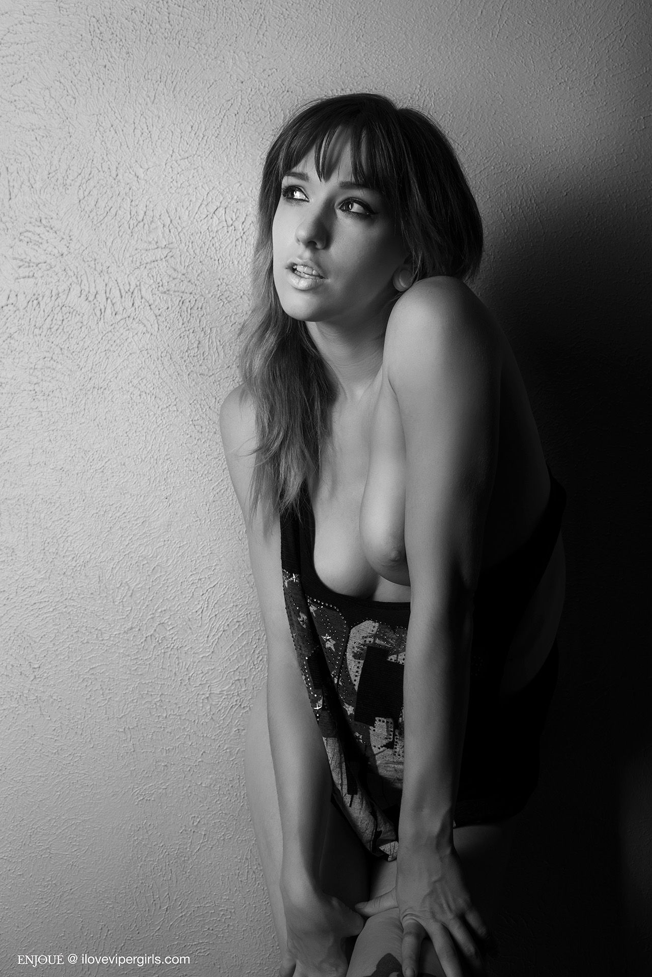 Saturn Werde topless looking away wearing a black Rock and Roll tank top.